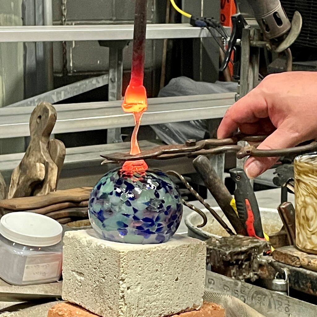 Friendship Globe glassblowing class artist instructor adds a dab of molten glass to finish the piece.