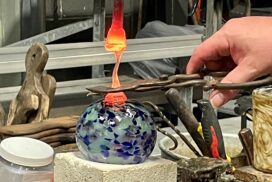 Friendship globe glass blowing class artist instructor adds a dab of molten glass to the piece.