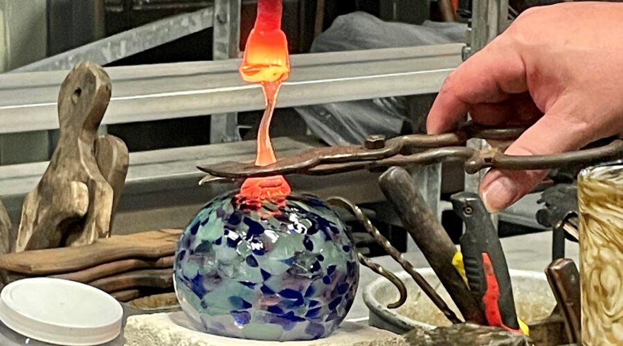 Friendship globe glass blowing class artist instructor adds a dab of molten glass to the piece.