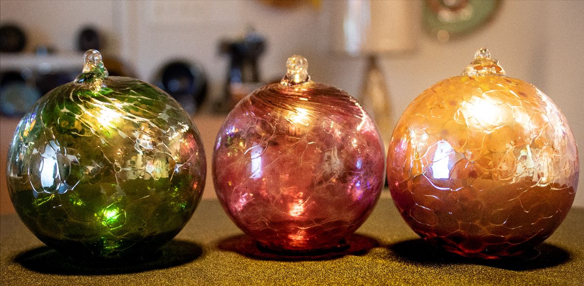 A trio of blown glass ornaments in festive holiday colors