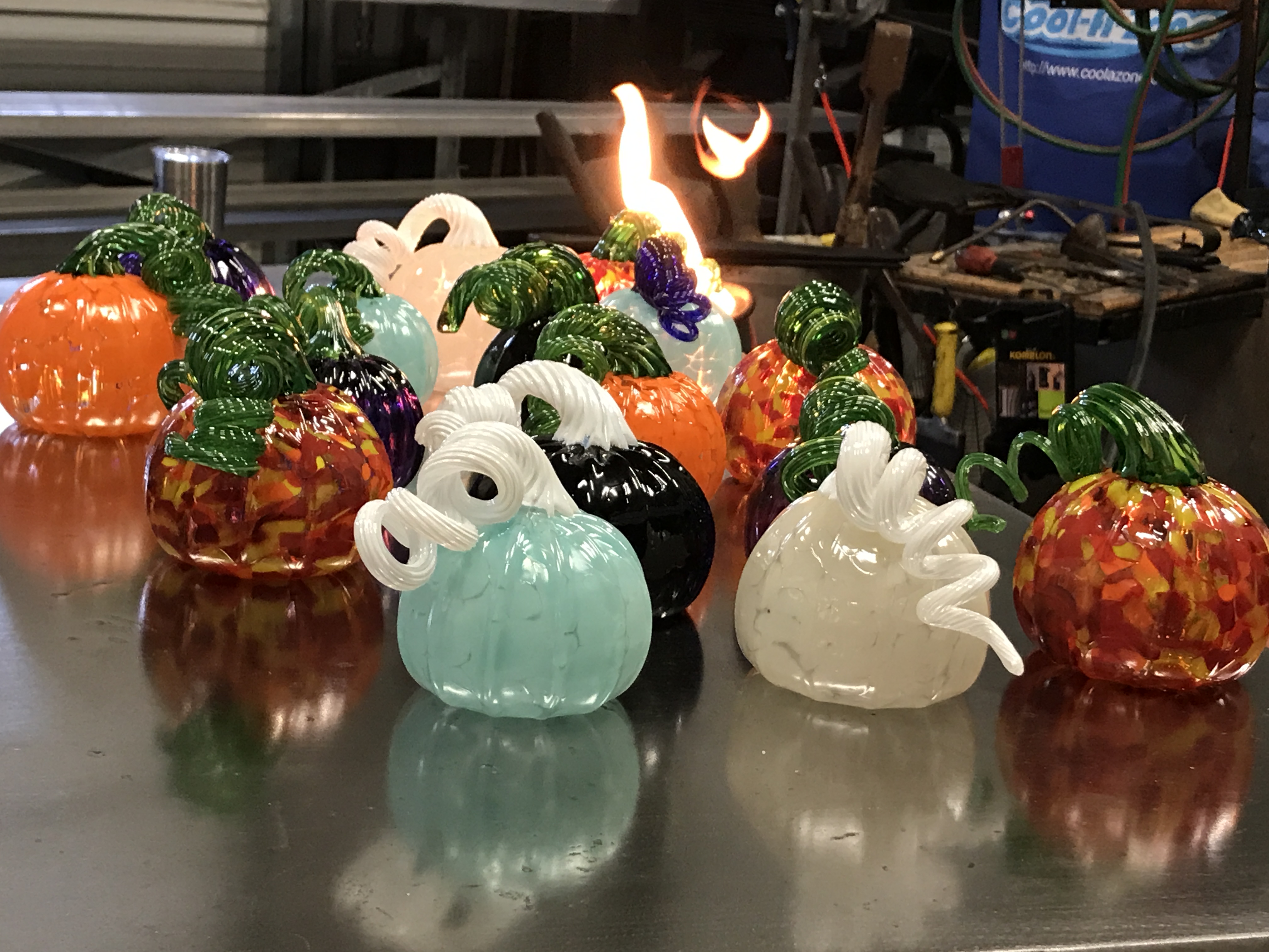 A group of miniature blown glass pumpkins in festive colors